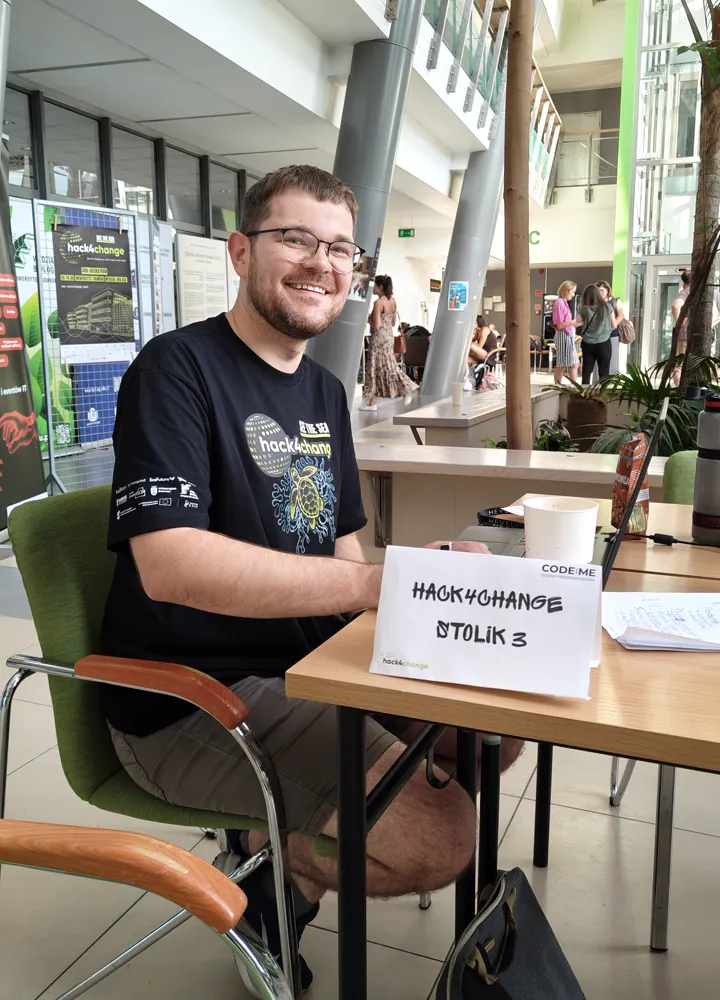 Kamil Rybacki przy stoliku numer 3 na hackathonie Hack4Change